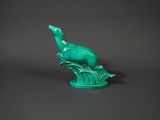 an image of a green statue of a bird on a tree branch