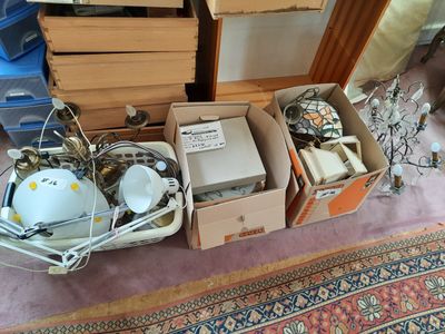 plusieurs cartons contenant des objets divers, posés sur un tapis dans une pièce