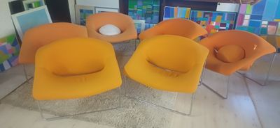 quatre chaises orange dans une pièce avec une bibliothèque