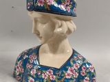 a ceramic figurine of a woman with a hat on her head