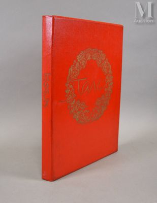 un livre rouge orné d'un logo doré, posé sur une surface blanche
