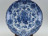 a blue and white plate with a man playing a musical instrument