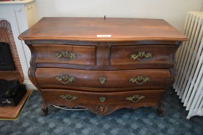 a wooden chest of drawers in a room next to a radiator