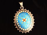 un gros plan d'un pendentif bleu et or sur fond noir