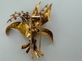 a gold brooch with flowers on it on a white surface