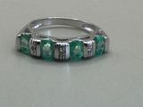a silver ring with green stones on a table