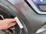 a hand that is holding a piece of paper near a car