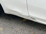 a white car that has been damaged and is parked on the side of the road