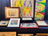 un ensemble d'œuvres d'art, encadrées et non encadrées, posées sur une table