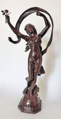 bronze statue of a woman holding a flower and a bird in her hand