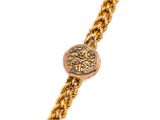 Gros plan sur un bracelet en chaîne en or sur lequel se trouve une pièce de monnaie