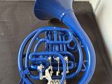 a blue french horn sitting on the floor next to a white wall
