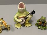 three figurines of frogs and a guitar on a table