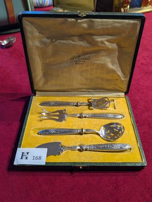 un service d'argenterie dans un coffret posé sur une table rouge