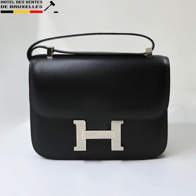 sac à main en cuir noir avec une poignée métallique sur un fond blanc