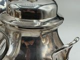 a silver tea pot sitting on a table next to a silver kettle
