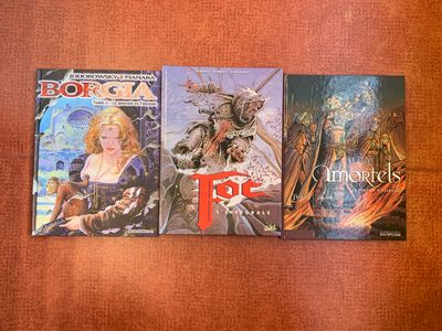 trois livres sont alignés sur une surface marron