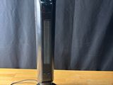 a black tower heater sitting on top of a wooden table