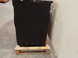 a black trash can sitting on a pallet in a warehouse