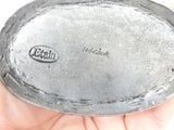 a person holding a silver plate with a logo on it