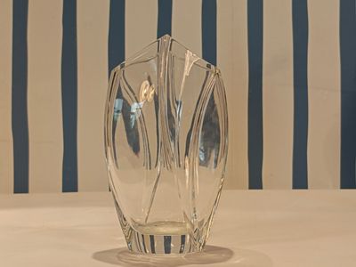 a glass vase sitting on a table with a striped wall behind it