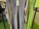 two sweaters on a rack in a store with clothes on hangers