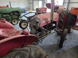 a pink tractor in a garage with other tractors in the background