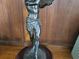 une statue représentant un garçon tenant un éventail, posée sur une étagère