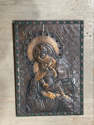 une photo d'une plaque métallique sur laquelle figure l'image d'une femme tenant un enfant dans ses bras