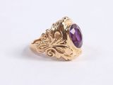 a close up of a gold ring with a purple stone