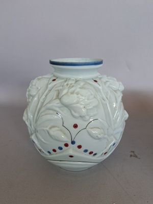 un vase blanc orné de motifs rouges et bleus