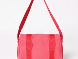 a pink handbag with a red strap and a red handle