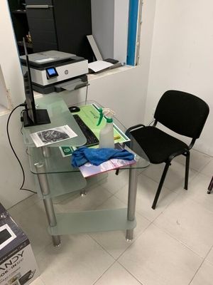 un bureau en verre sur lequel se trouvent un ordinateur et une imprimante