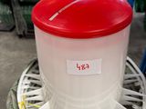 un récipient en plastique muni d'un couvercle rouge, posé sur une étagère