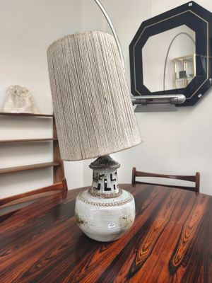 une table sur laquelle se trouve une lampe, avec un miroir en arrière-plan