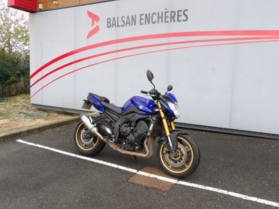 une moto bleue garée devant un immeuble