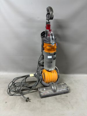 un aspirateur est posé par terre près d'un mur