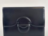 the black leather clutch bag has a metal ring on the front