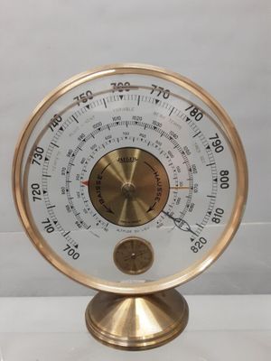 une horloge dorée et blanche posée sur un socle, elle-même posé sur une table