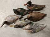 six canards en bois sont alignés sur une surface blanche