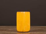 an orange vase sitting on top of a wooden table next to a black wall