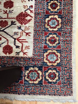 une photo d'un tapis posé sur un parquet, avec les pieds d'une personne
