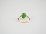 a gold ring with a green jade stone