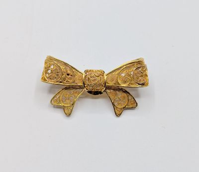 une image représentant une broche en forme de nœud dorée sur fond blanc