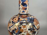 un vase orange et bleu posé sur une table blanche