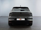 the back end of a grey car in a room with a white wall