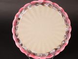 une pâte à tarte dans un moule à tarte rose posé sur une table noire