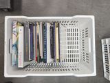 a white basket with books in it on the floor