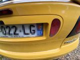 a close up of a yellow car with a license plate on it