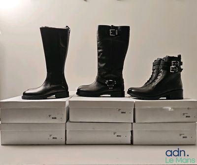 trois paires de bottes noires sont posées sur des cartons